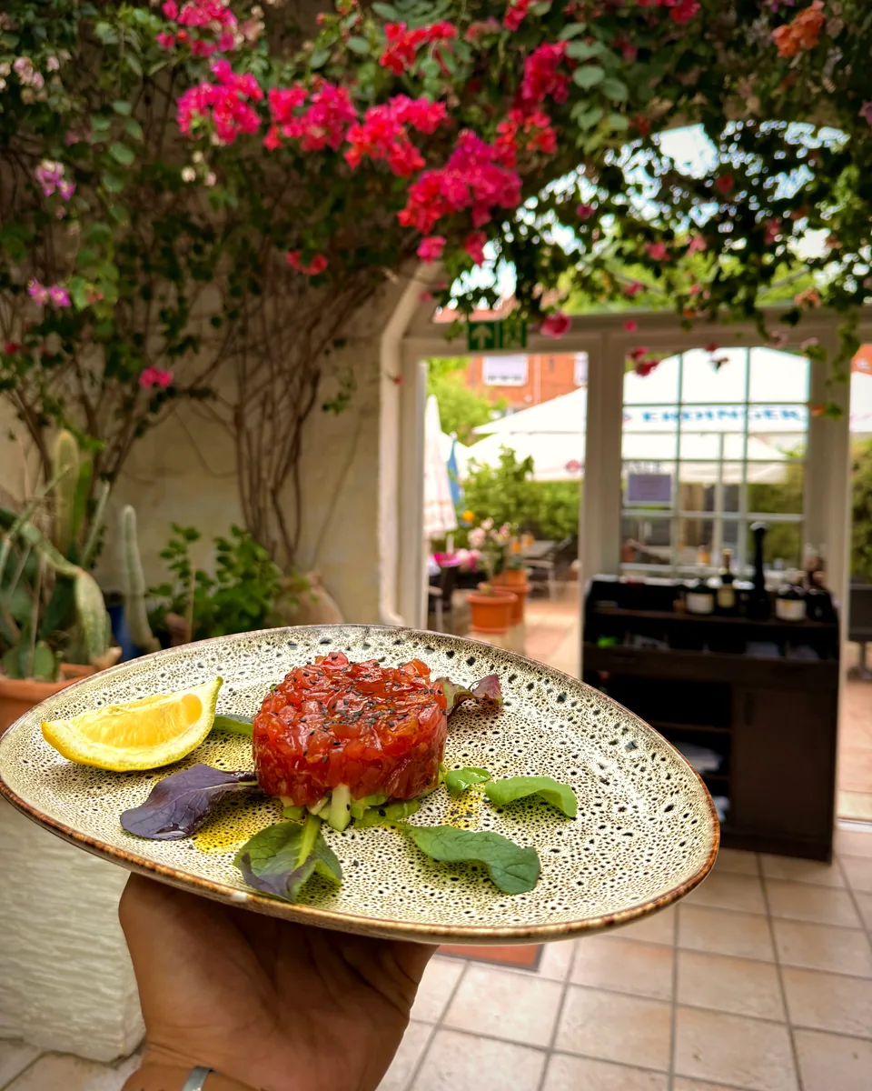 Rindertatar auf der Terrasse von La Taverna, im Hintergrund blühende Bougainvillea